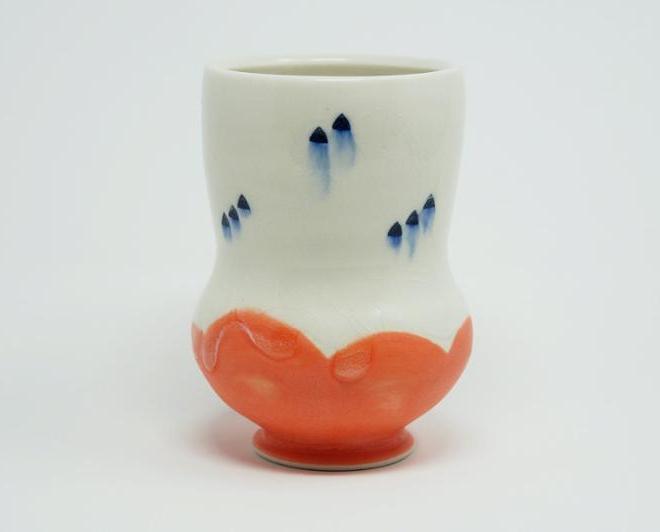一个白色陶瓷杯，上面有蓝点和鲑鱼底. 