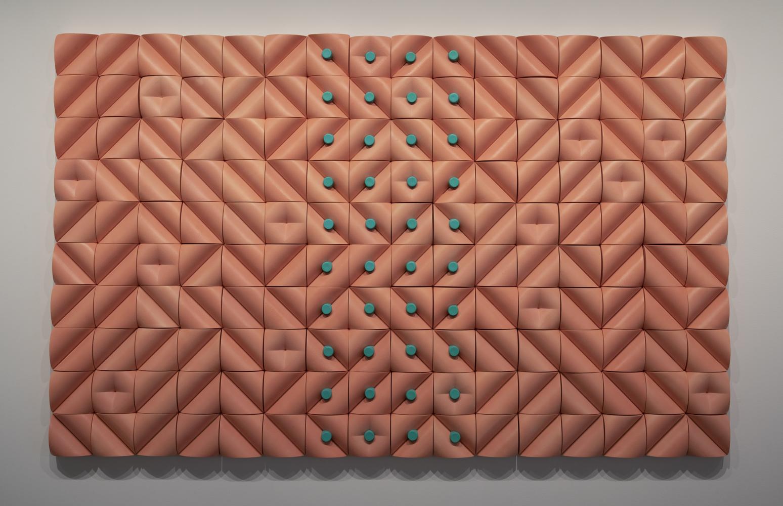 a large, pink, rectangular tile piece of a geometric design featuring green dots in the middle